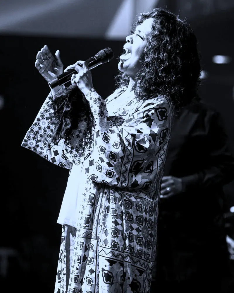 The artist mid song with one hand raised, the band behind her.