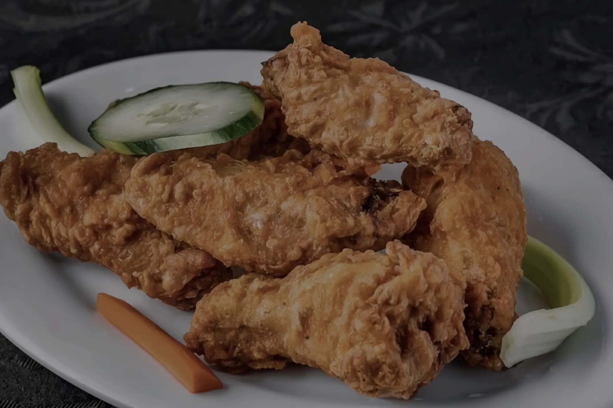 Fried chicken wings plated with cucumber and celery.