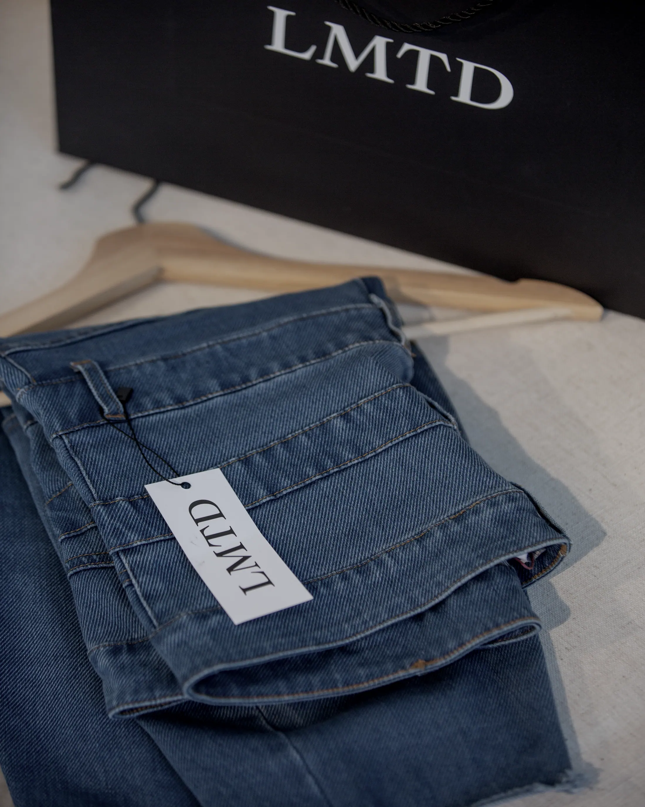 Folded denim on a wooden hanger with the hang tag turned out.